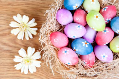 Paskalya yumurtaları bir yuva saman üzerinde papatya ile dekore edilmiştir