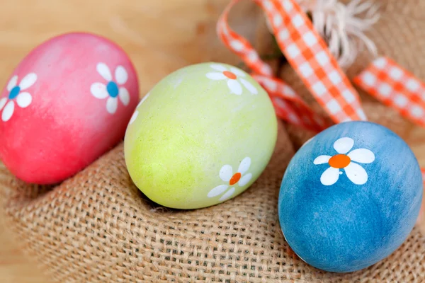 Пасхальные яйца, украшенные маргаритками и мешком — стоковое фото