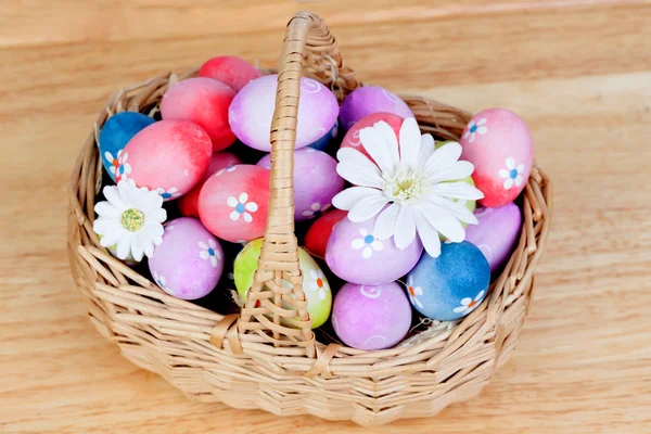 Пасхальные яйца, украшенные маргаритками, спрятанными в корзине — стоковое фото