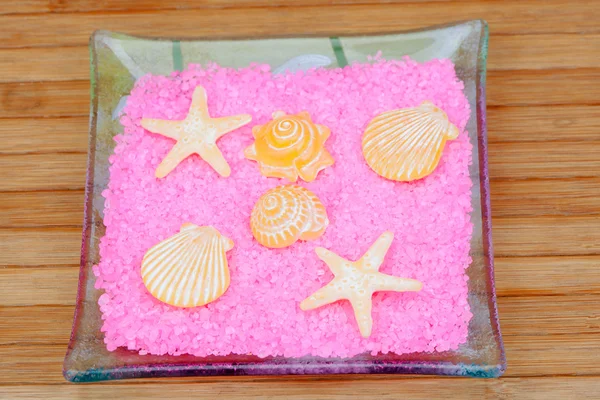 Jabones con formas de conchas y estrellas de mar en sales de baño de color rosa en un — Foto de Stock