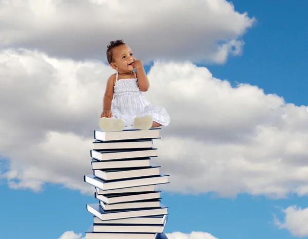 Menina africana sentado em uma pilha alta de livros — Fotografia de Stock