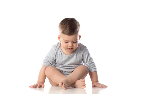 Çıplak Ayakla Bembeyaz Zeminde Oturan Vücutlu Gülümseyen Bir Bebek — Stok fotoğraf