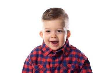 Beyaz duvar arkasında gülümseyen şık giyinen küçük bir çocuk. 