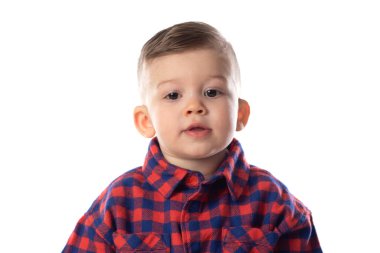 Beyaz duvar arkasında gülümseyen şık giyinen küçük bir çocuk. 