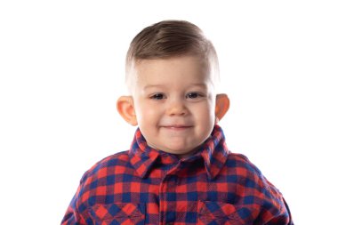 Beyaz duvar arkasında gülümseyen şık giyinen küçük bir çocuk. 