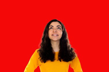 Esmer, dalgın bir kız kırmızı arka plana bakıyor.