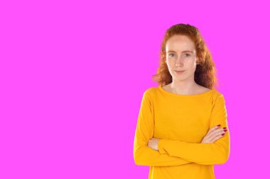 Yakın plan, çekici, kızıl saçlı, uzun sağlıklı saçlı, gülümseyen kamera pembe arka planda.