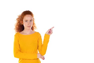 Genç, güzel bir kadın kendinden emin bir şekilde gülümsüyor. Beyaz arka plana karşı pozitif, rahat ve tatmin edici bir tavır sergiliyor.