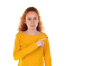 Genç, güzel bir kadın kendinden emin bir şekilde gülümsüyor. Beyaz arka plana karşı pozitif, rahat ve tatmin edici bir tavır sergiliyor.