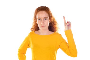 Genç, güzel bir kadın kendinden emin bir şekilde gülümsüyor. Beyaz arka plana karşı pozitif, rahat ve tatmin edici bir tavır sergiliyor.