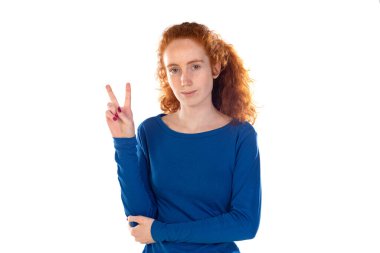 Çekici, kızıl saçlı, neşeli bir kızın portresi beyaz arka planda izole edilmiş bir şekilde eğleniyor. 