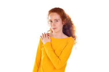 Sırt ağrısı çeken genç, kızıl saçlı bir kadın. Omzuna eliyle dokunuyor. Beyaz arka planda izole edilmiş kas ağrısı.