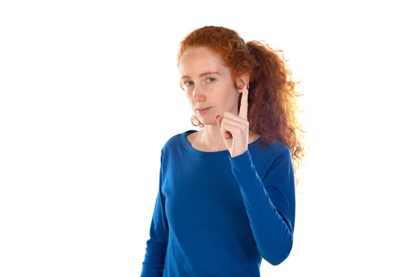青のTシャツを着た若い美しい赤毛の女性が白い隔離された背景の上に立っている 指を上げて怒りの表情で指差す ジェスチャーを示さない — ストック写真