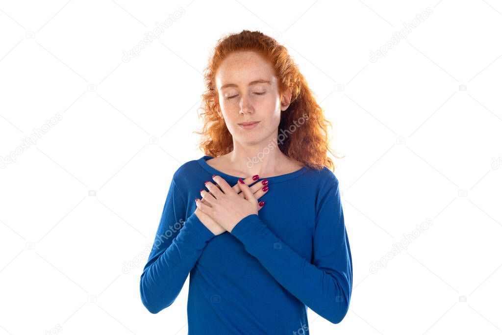 Sincere redhead woman holds hands together praying pose over white background