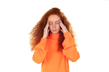 Genç, mutsuz, kırmızı saçlı, turuncu formalı, korkunç baş ağrısı ve migrenden muzdarip, yüksek tansiyonlu, güçlü bir ağrı hisseden, beyaz stüdyo arka planında izole edilmiş, yorgun ve yorgun bir kadın.. 