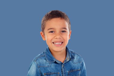 Latin child with denim shirt looking at camera and laughing isolated on a blue background 