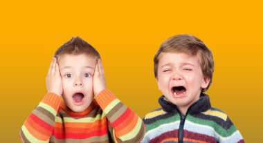 Two funny small brothers showing emotions isolated on a orange background