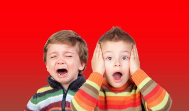 Two funny small brothers showing emotions isolated on a color background