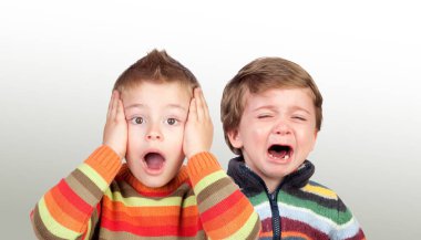 Two funny small brothers showing emotions isolated on a white background