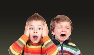 Two funny small brothers showing emotions isolated on a color background