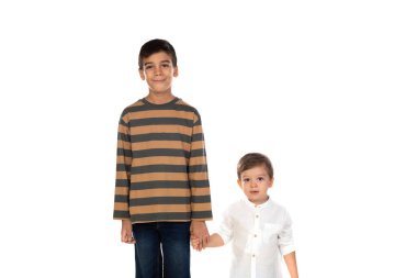 Küçük kardeşiyle el ele tutuşan güzel çocuk beyaz bir arka planda izole edilmiş.