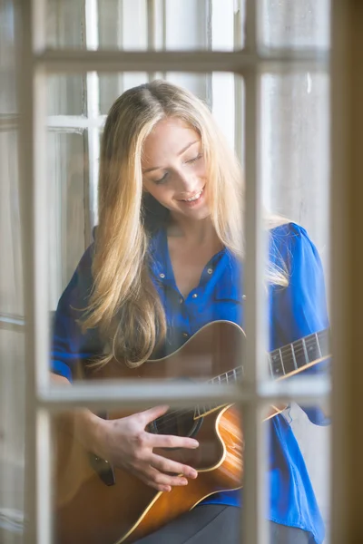 Молода жінка грає на гітарі на вікні — стокове фото