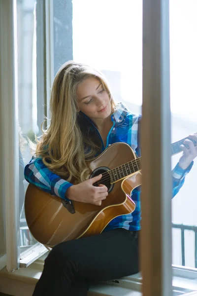 Giovane donna che suona la chitarra sulla finestra — Foto Stock