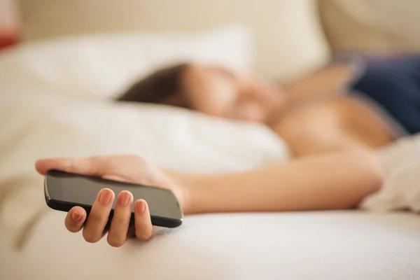 Lying in bed and holding mobile phone — Stock Photo, Image