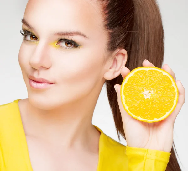 Young brunette with orange in her hand — Stock Photo, Image