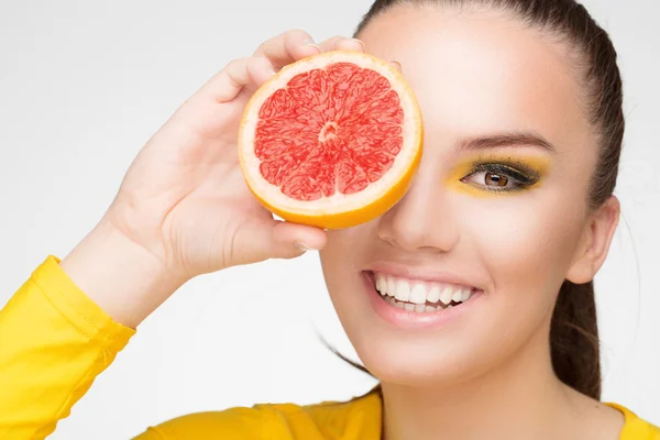 Mladá brunetka s červeného grapefruitu v ruce — Stock fotografie