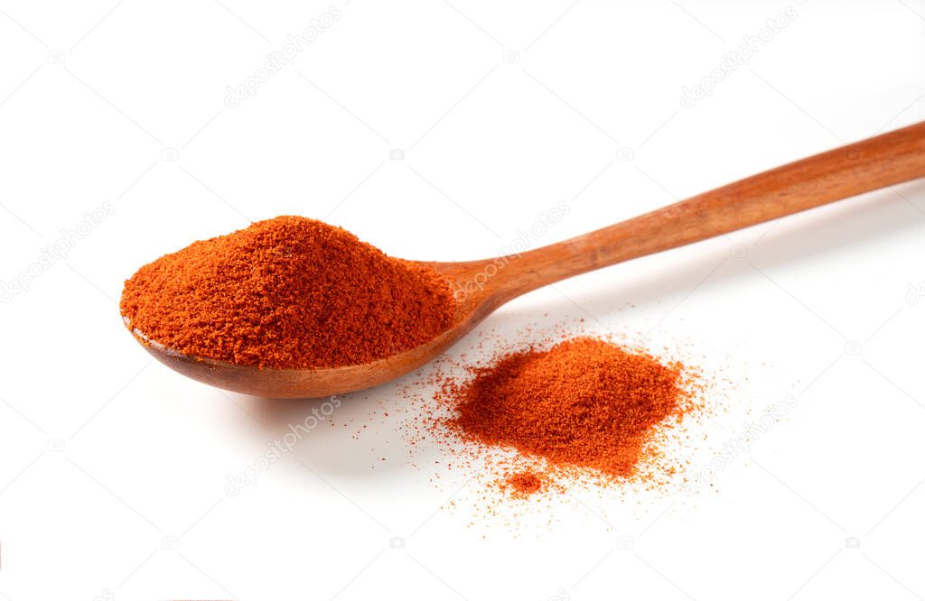 Red pepper powder and wooden spoon placed on a white background. Cayenne pepper. Paprika powder