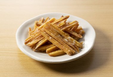 Imokempi tahta bir arka plana yerleştirilmiş. Imokempi, tatlı patateslerden yapılmış ve şekerle kaplanmış bir Japon tatlısıdır..