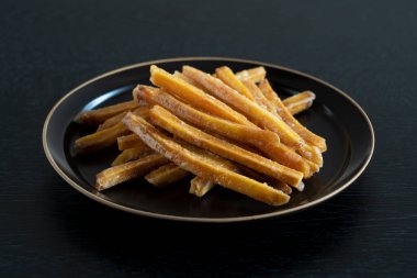 Imokempi tahta bir arka plana yerleştirilmiş. Imokempi, tatlı patateslerden yapılmış ve şekerle kaplanmış bir Japon tatlısıdır..