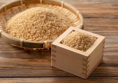 Tahta bir kutuda kahverengi pirinç ve ahşap bir arka plana yerleştirilmiş bambu kevgir..