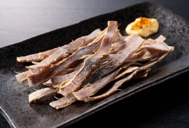 Siyah arka planda kurutulmuş mürekkep balığı ve mayonez. Surume bir Japon aperatifidir..