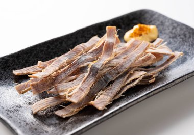 Beyaz bir zemine yerleştirilmiş tabakta kurutulmuş mürekkep balığı ve mayonez. Surume bir Japon aperatifidir..