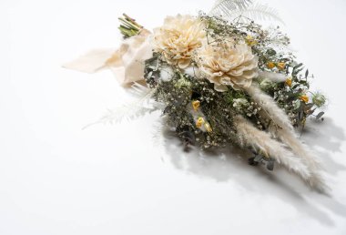 Beyaz arka plana yerleştirilmiş bir buket kurumuş çiçek. Düğün, festival konsepti.