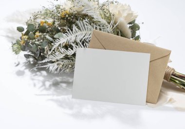 Dried flower bouquet and blank message card placed on white background. Wedding and celebration concept.