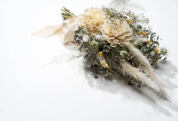 Beyaz arka plana yerleştirilmiş bir buket kurumuş çiçek. Düğün, festival konsepti.