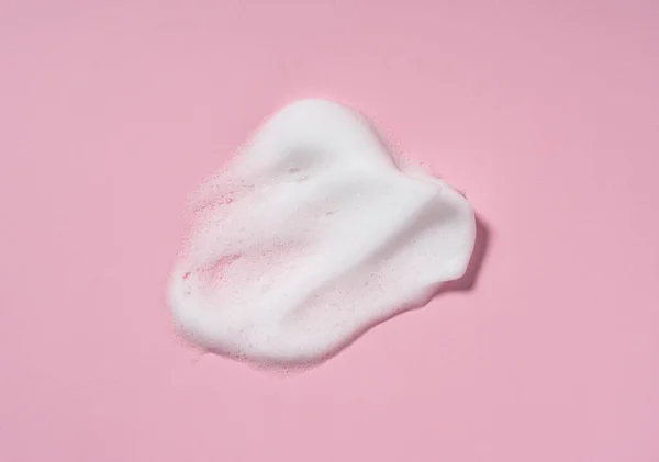 Skincare cleanser foam texture. Swatches of soap, shampoo and cleansing mousse foam with copy space on pink background. Close-up of facial cleansing soap.