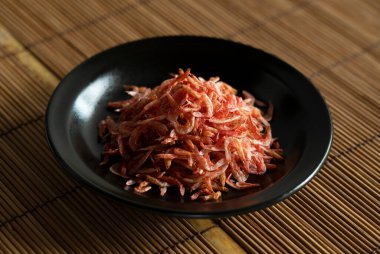 Bambu yemek hasırına konmuş tabakta kurutulmuş sakura karidesi. Japon yemeğinin görüntüsü..