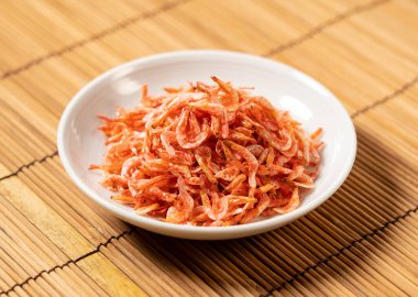 Dried sakura shrimps on a plate placed on a bamboo luncheon mat. Image of Japanese food. 