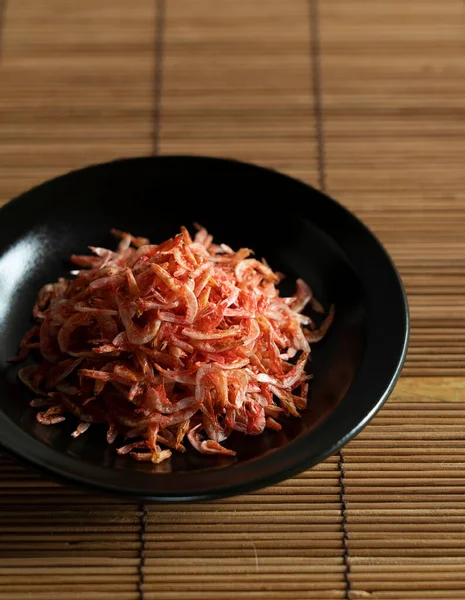 在放在竹子午餐垫子上的盘子里的干腊肠虾仁 日本食品的形象 — 图库照片
