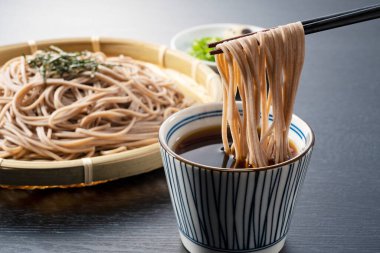 Zaru-soba siyah arka plana yerleştirilmiş. Erişte çorbasına batırılmış soba eriştesi. Zaru soba geleneksel bir Japon yemeğidir..