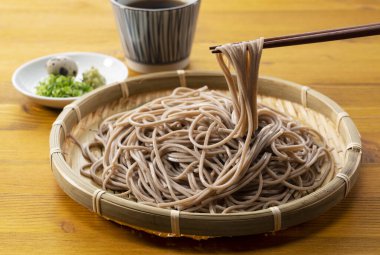 Zaru-soba ve ahşap masadaki baharatlar. Çubuklu soba eriştesi al. Zaru Soba geleneksel bir Japon yemeğidir..