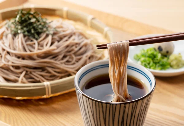 Zaru-soba ve ahşap masadaki baharatlar. Soba erişteleri erişte çorbasına batırılır. Zaru soba geleneksel bir Japon yemeğidir..