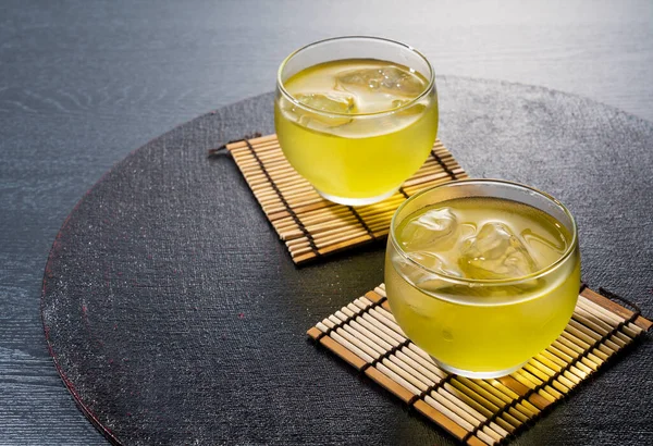 Cold Japanese green tea on a black tray. Green tea with ice.