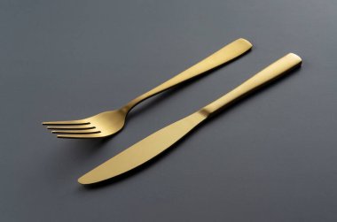 Gold knives and forks set against a black background. Beautiful gold cutlery. 