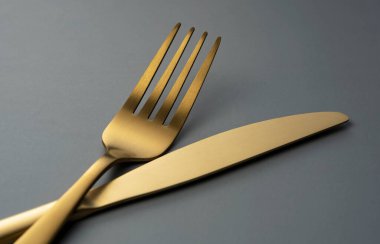 Gold knives and forks set against a black background. Beautiful gold cutlery. Close-up.