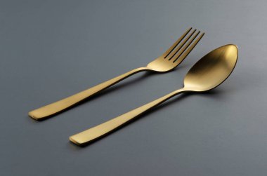 Gold knives and spoons set against a black background. Beautiful gold cutlery. 